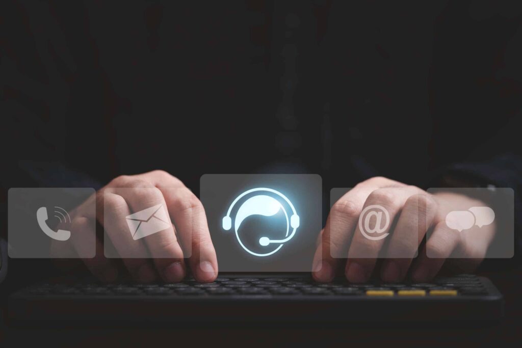 Mão de homem digitando em uma tela, com ícones de canais de atendimento integrado.