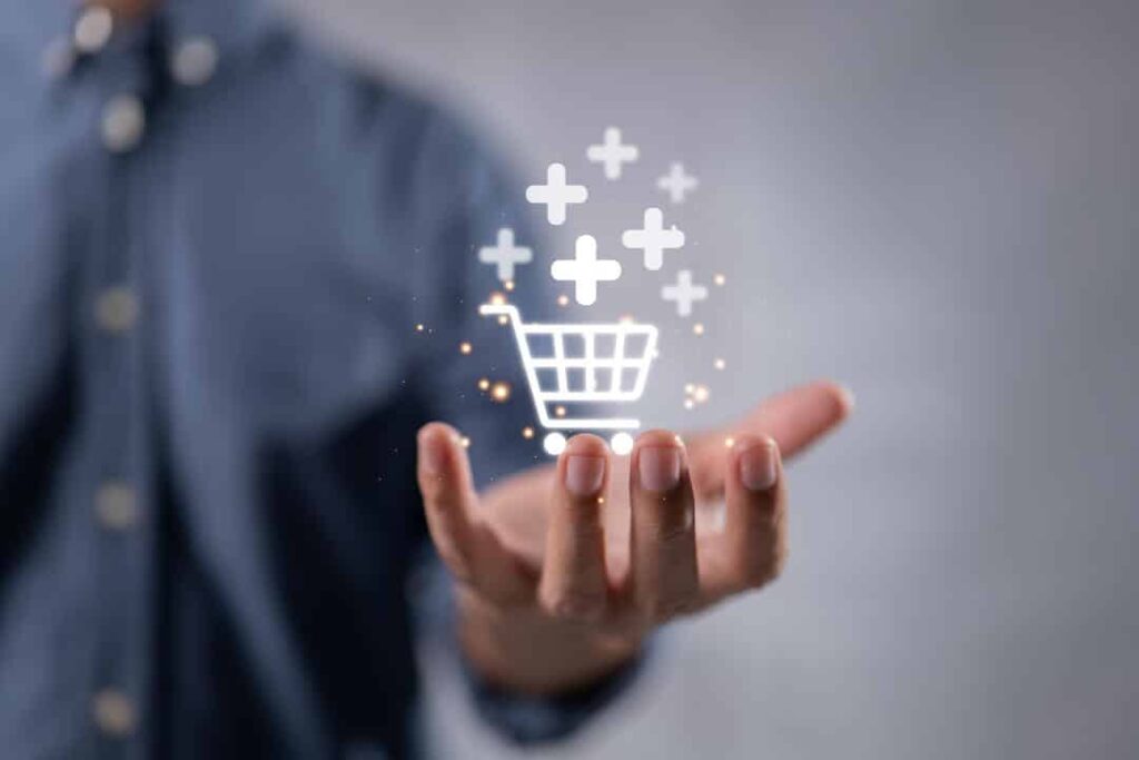 Homem com a mão aberta, a palma virada pra cima, projetando um carrinho de comprar com sinais de + em volta, representando o cross-selling.