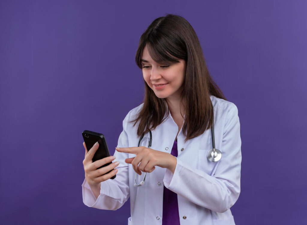 Mulher do setor da saúde mexendo no celular onde atende pelo WhatsApp alguns pacientes.