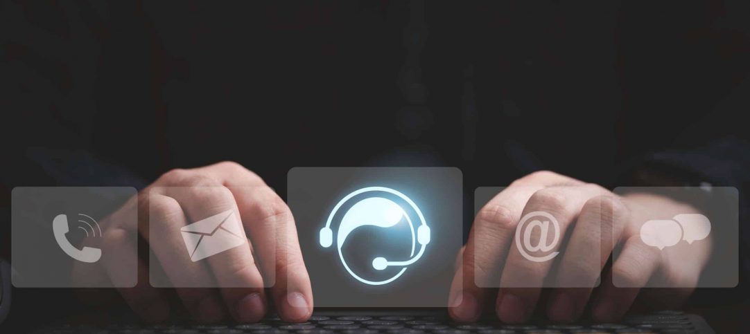 Mão de homem digitando em uma tela, com ícones de canais de atendimento integrado.