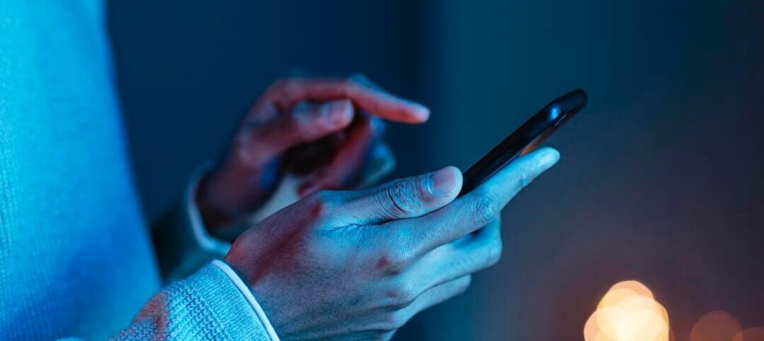 Mãos segurando um celular, verificando a nova atualização dos canais WhatsApp.