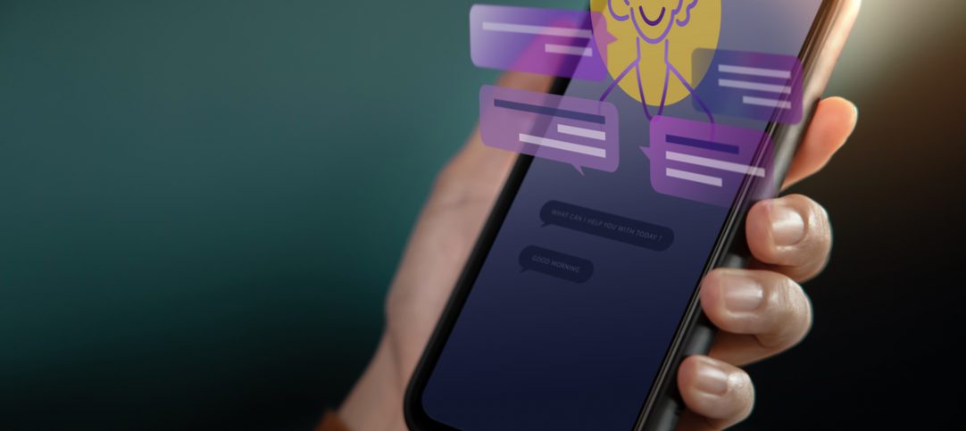Pessoa segurando um celular onde é possível ver uma conversa com um chatbot humanizado.