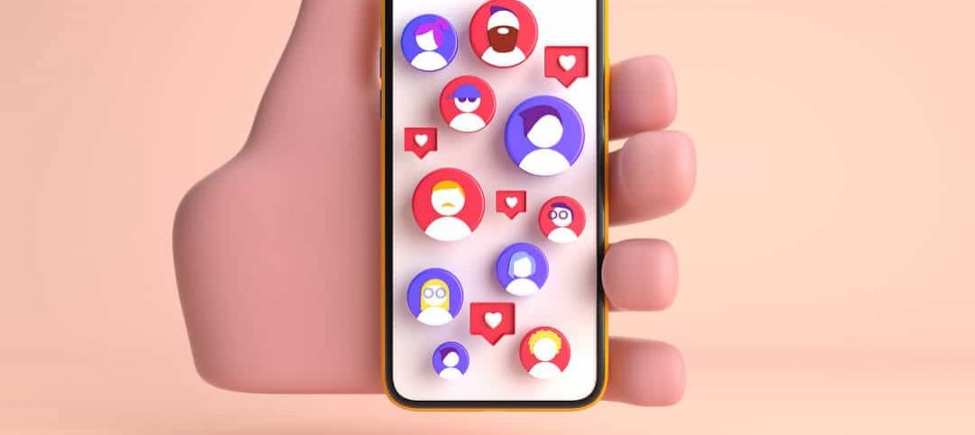 Vetor de mão segurando um celular com a tela cheia de perfis de pessoas e corações, representando o marketing de relacionamento.