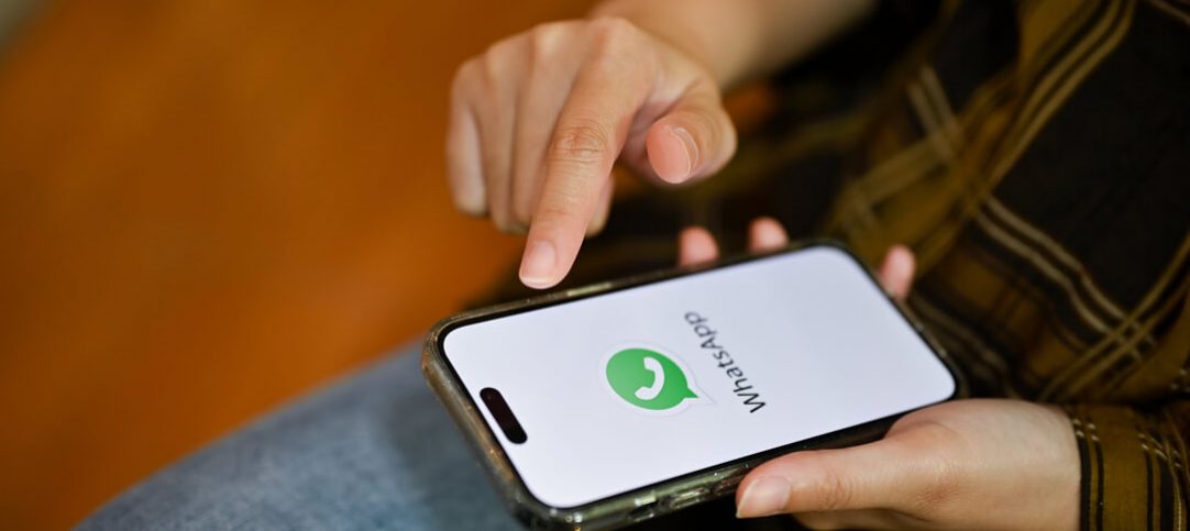 Mãos femininas segurando um celular com a logo do WhatsApp enquanto acessa o SAC da empresa.