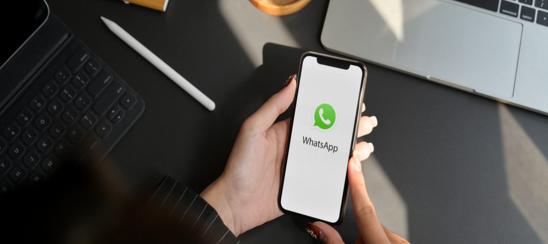 Mulher de negócios com o aplicativo do Whatsapp aberto no seu celular, tentando entender as mudanças de cobrança do WhatsApp.