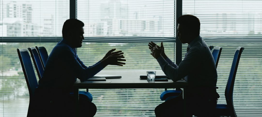 Na imagem observamos dois homens de negócios conversando em uma mesa e aplicando diferentes tipos de negociação.